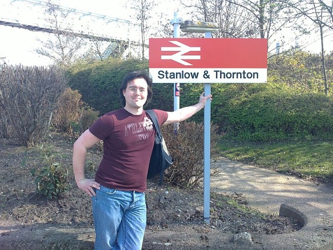 Scott in front of the Stanlow & Thornton station sign