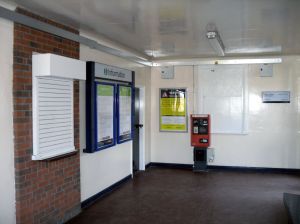 Inside Acton Bridge Station Building Photo of Interior of Acton Bridge Station Building, showing disused ticket window, posters and a Permit to Travel machine
