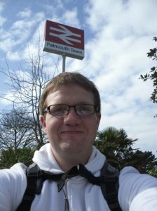 Photo of Robert standing under the Falmouth Town station sign