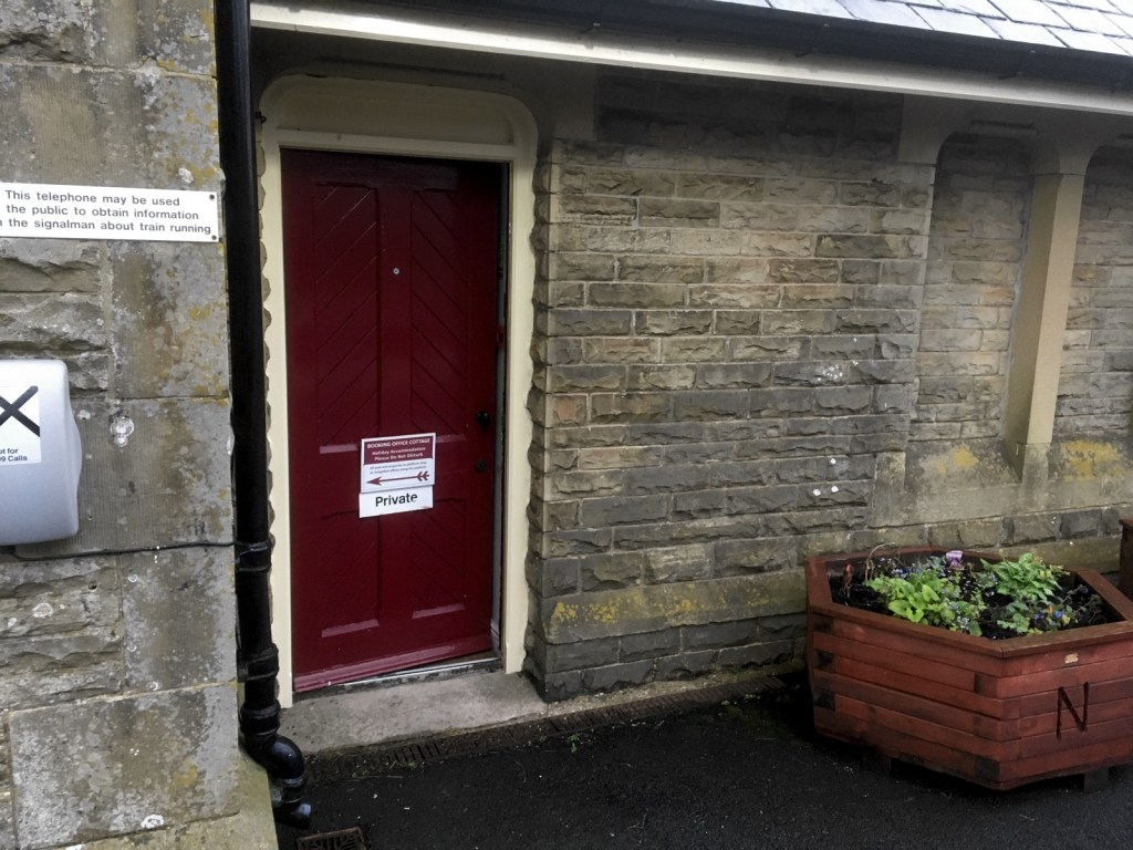 Red door entrance to Booking Office Cottage from the platform at Kirkby Stephen station